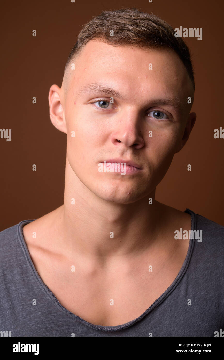 Young man wearing gray shirt against brown background Stock Photo