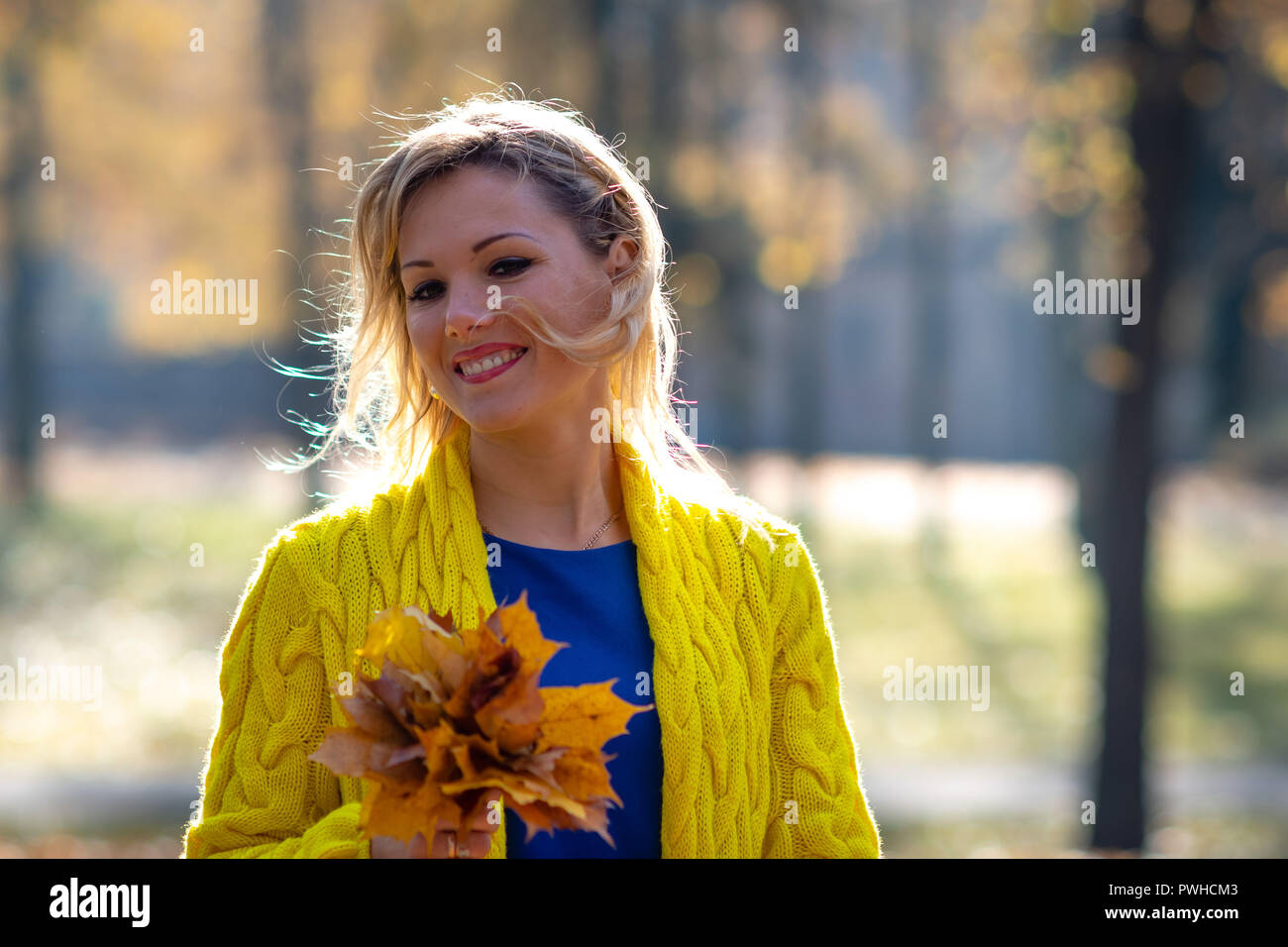 A young, beautiful, blonde woman walking through the autumn park and ...