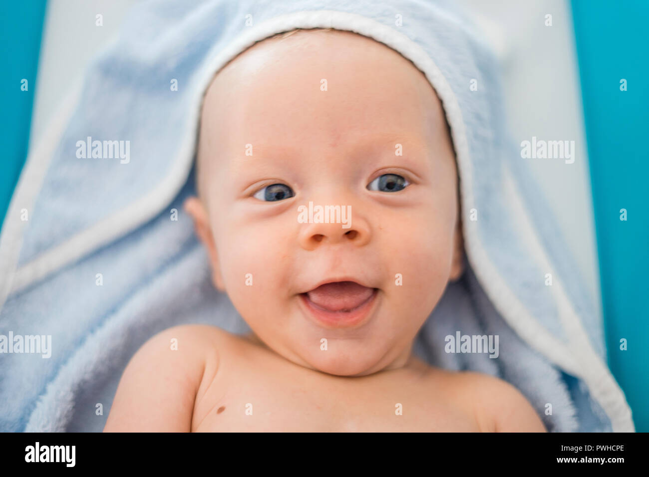 Happy baby boy with blue eyes laying in cute blue towel Stock Photo Alamy
