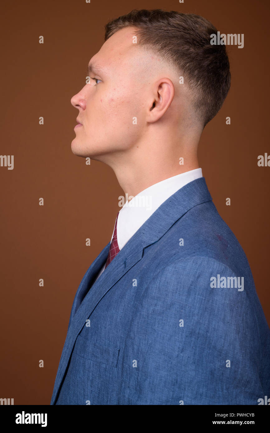 Young businessman wearing suit against brown background Stock Photo - Alamy