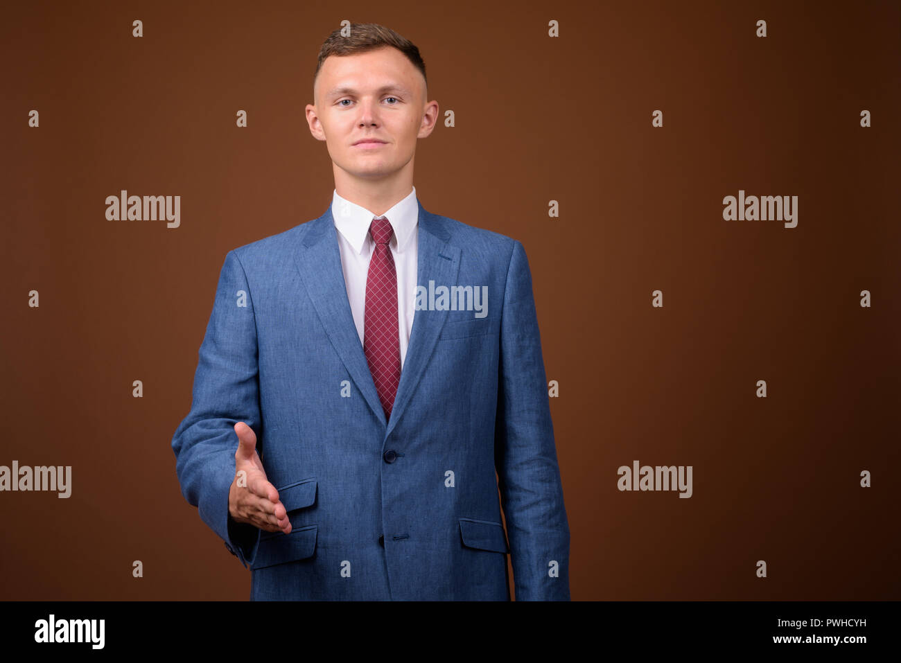 Young businessman wearing suit against brown background Stock Photo