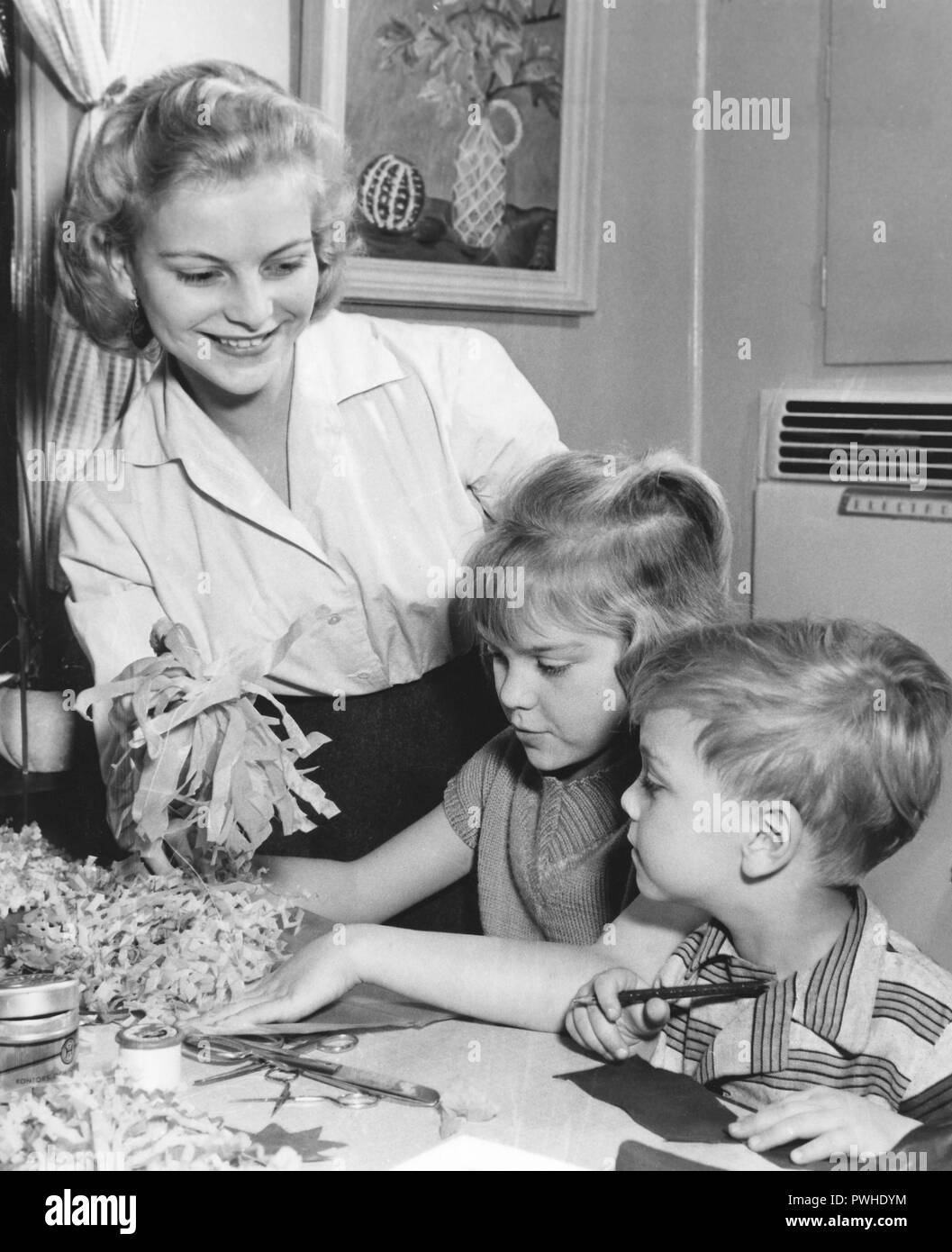 Christmas in the 1950s. Anita Björklund who is chosen to be Stockholms Lucia 1957, is christmas decorating with her younger sister and brother. Stock Photo