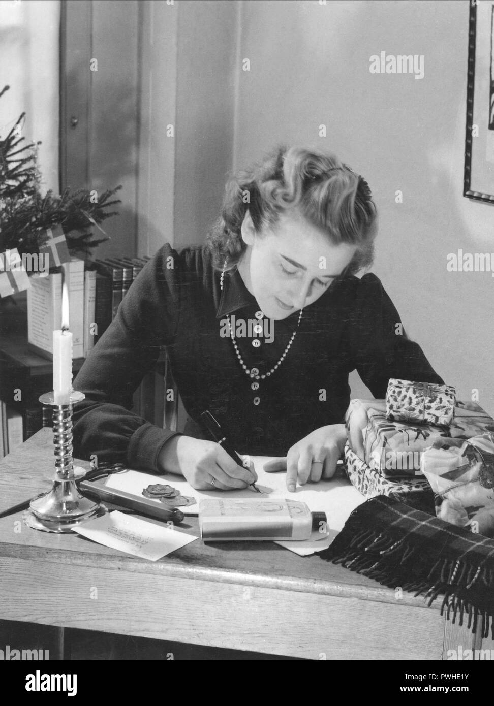 Christmas in the 1940s. A woman is wrapping christmas gifts. Sweden 1940s Stock Photo