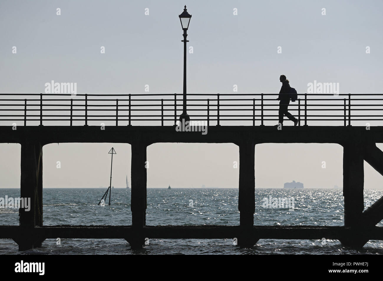 A person walks along a pier next to the Hot Walls in Old Portsmoouth. Stock Photo