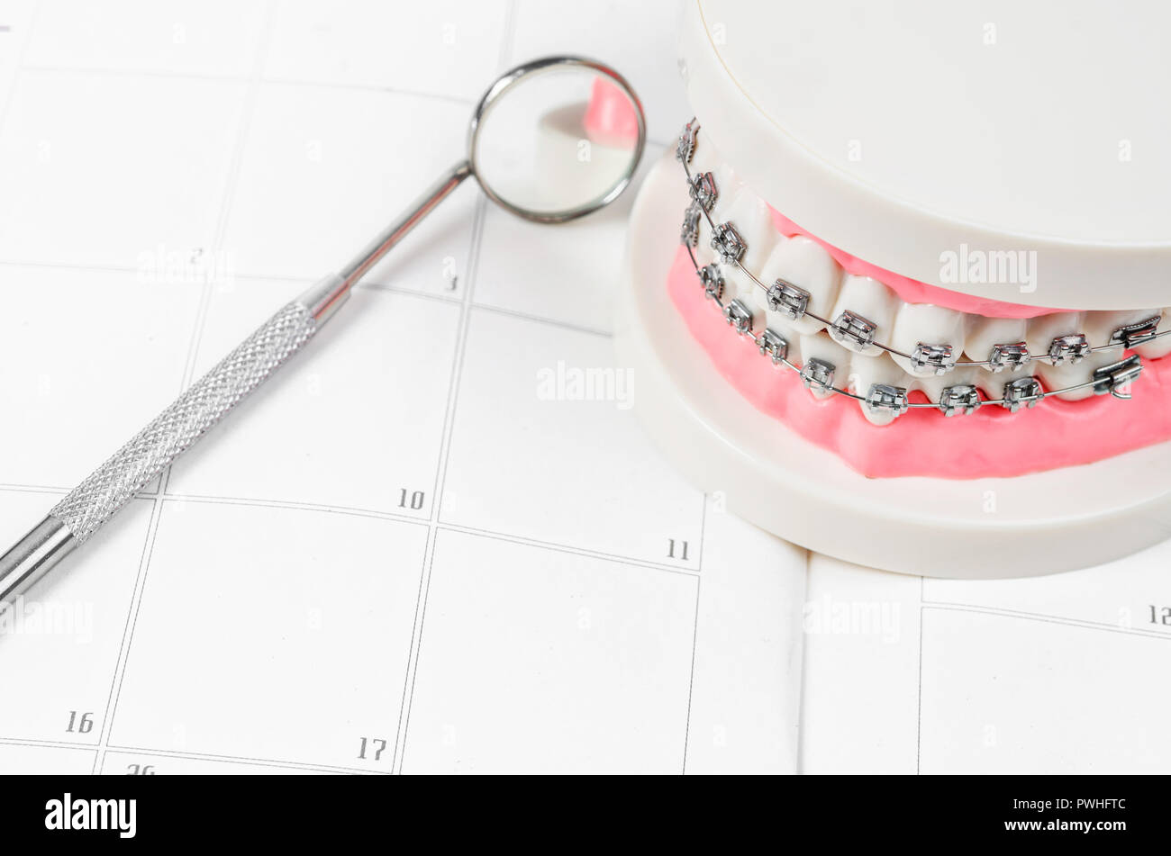 Tooth model with metal wire dental braces on a calendar. Regular ...