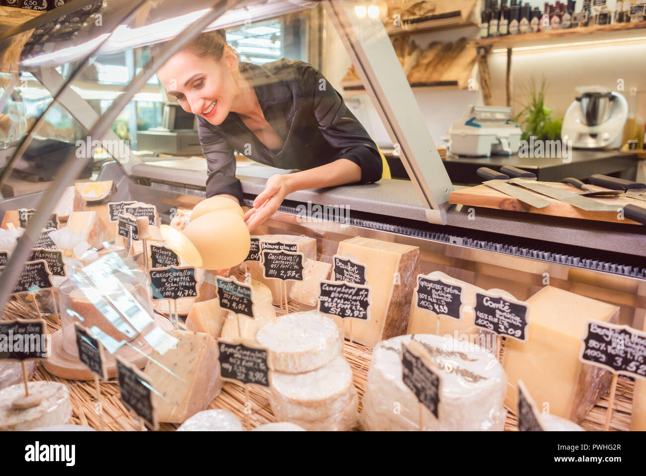 Shop clerk woman sorting cheese in the supermarket display Stock Photo