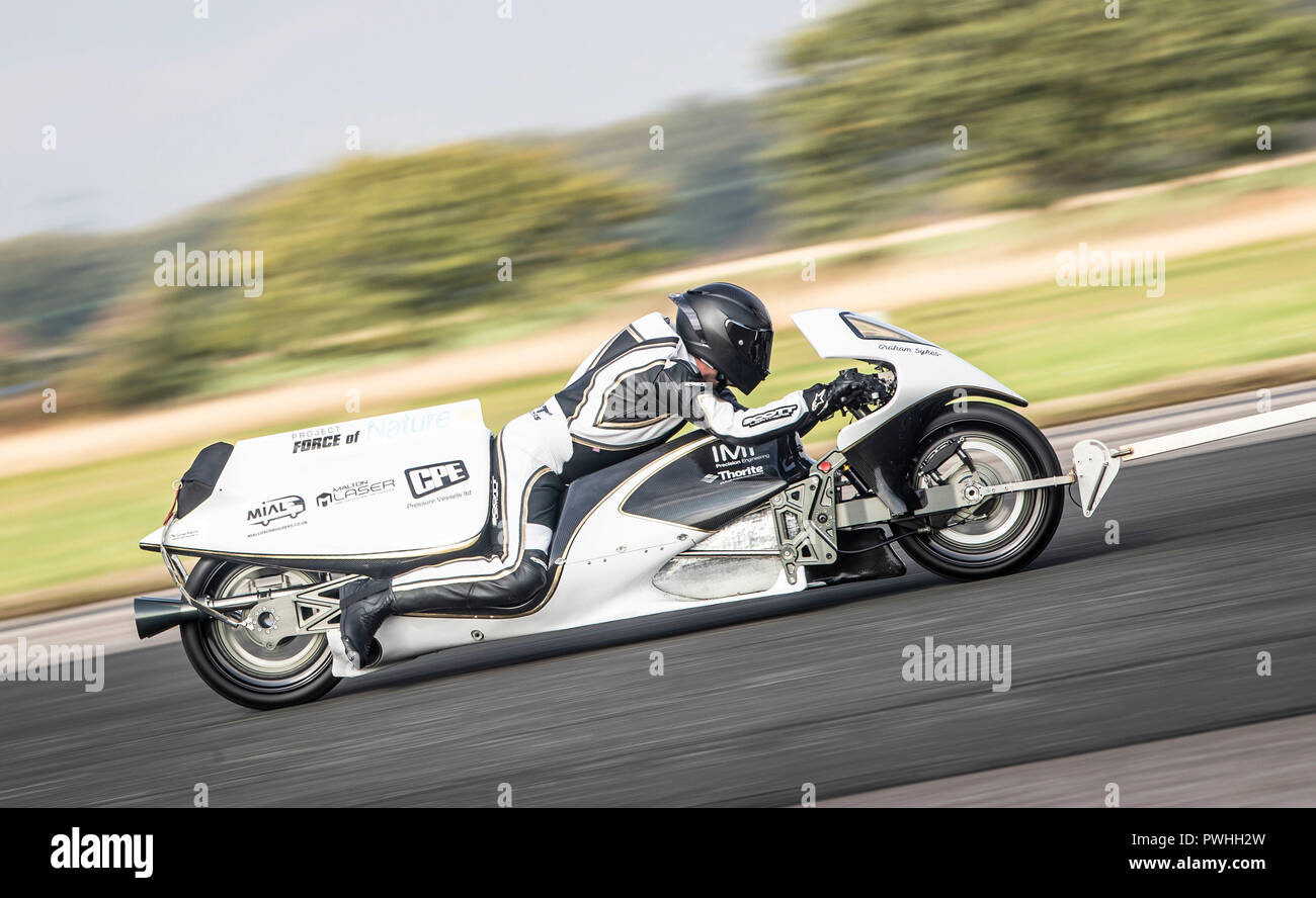 Graham Sykes on his 'Force of Nature' steam rocket bike is towed behind a van, as he tests his bike in preparation for his world land speed record attempt for a steam powered vehicle, during the Straightliners top speed & wheelie event at Elvington Airfield in Yorkshire. Stock Photo