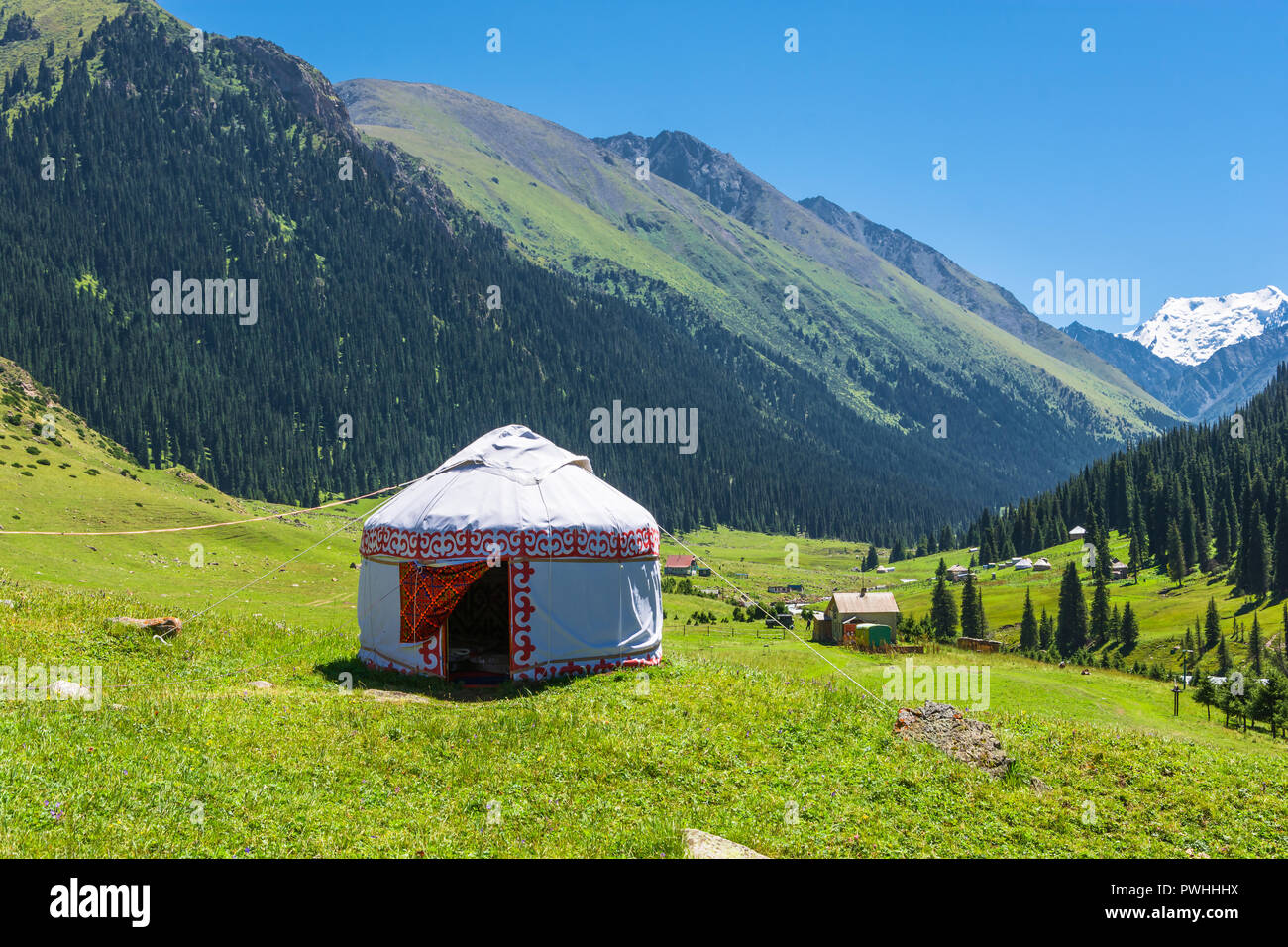 Beautiful mountain landscape with the white Yurt, decorated with a red ornament, Kyrgyzstan. Stock Photo