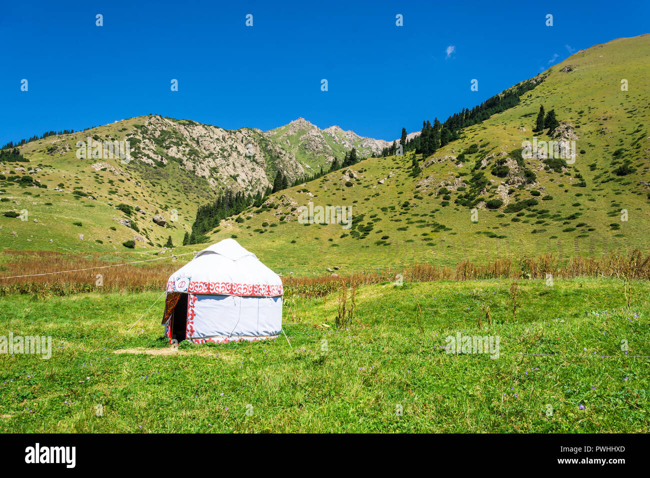 Beautiful mountain landscape with the white Yurt, decorated with a red ornament, Kyrgyzstan. Stock Photo
