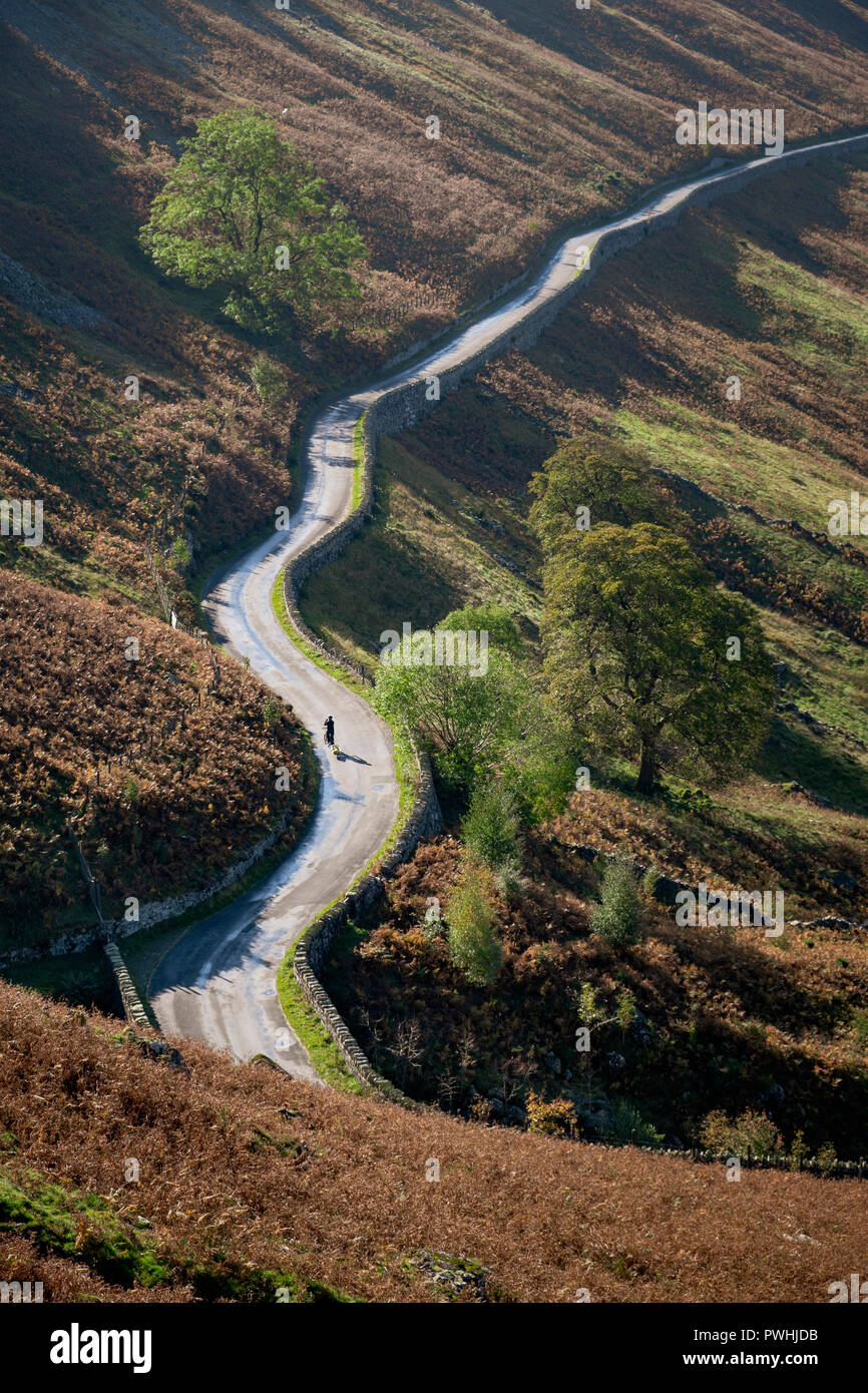 Lone cyclist on long winding road to Dudderwick Mardale Haweswater  Cumbria Lake District Stock Photo