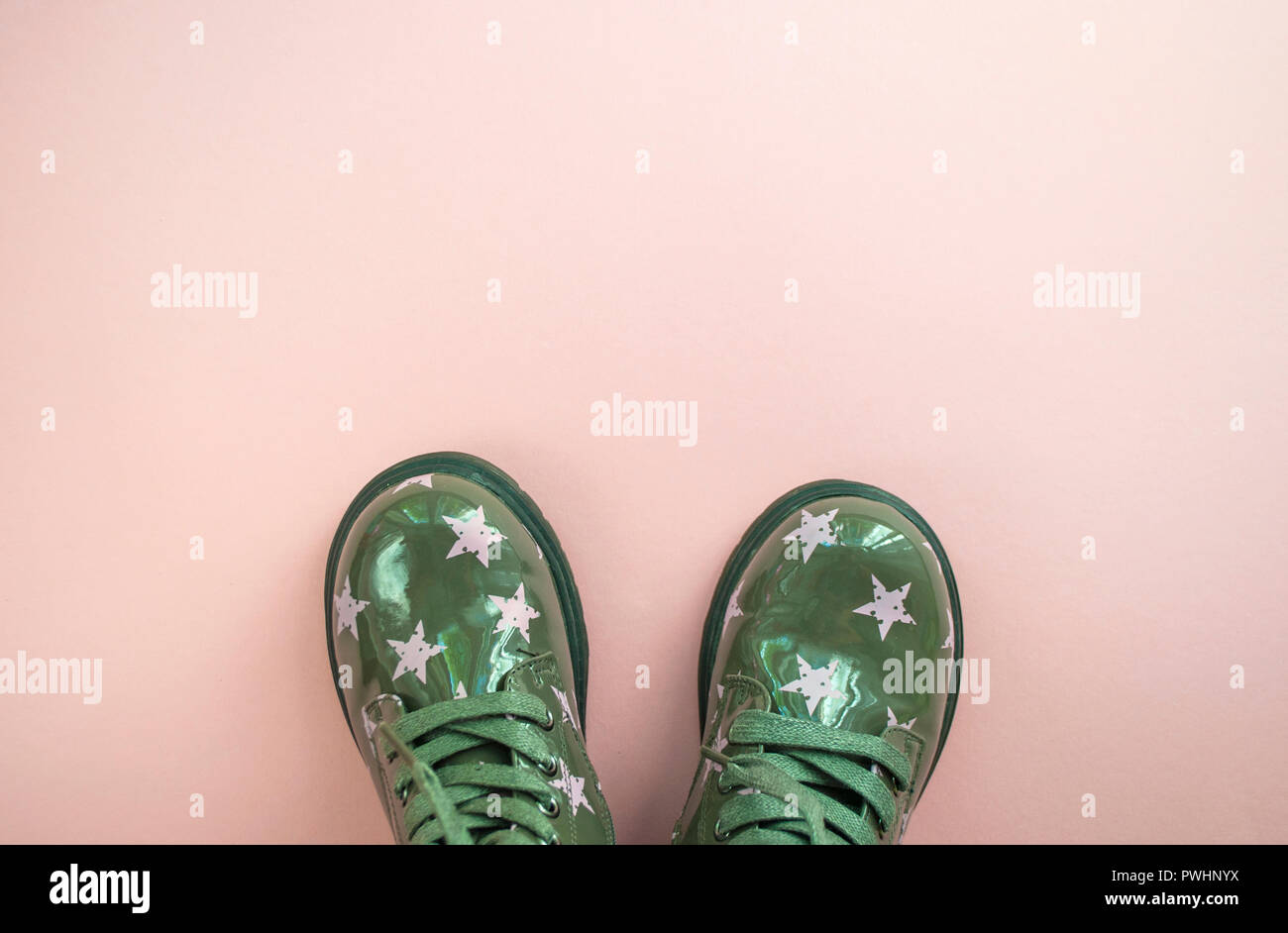 Flat lay of cute child's green color shoes on pink background with ...
