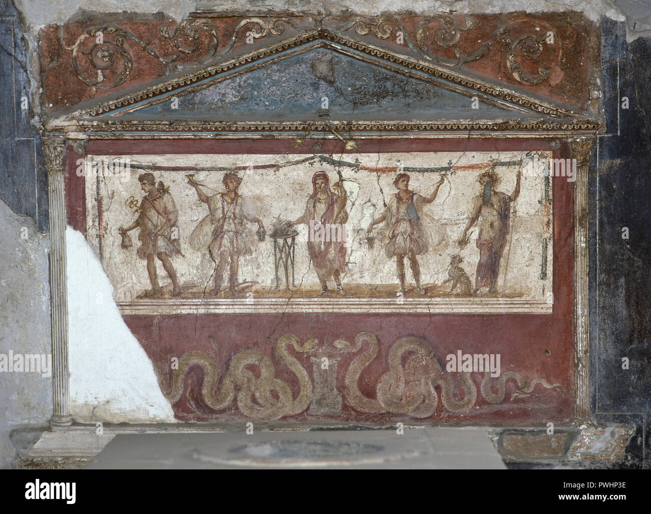 Pompeii. Lararium of the Thermopolium of Asellina. For a domestic cult. Frescoes depicting the Genius of the Pater Family among Lares (protective gods) making offerings. At his feet, the great serpent Agathodaimon. La Campania. Italy. Stock Photo