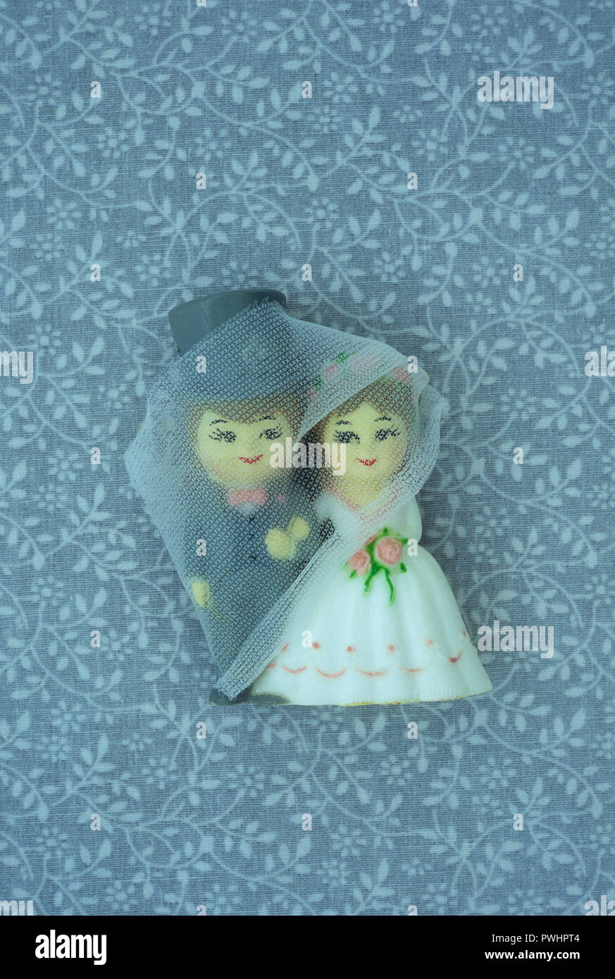 Model of cute wedding couple standing in front of simple floral wall covering Stock Photo