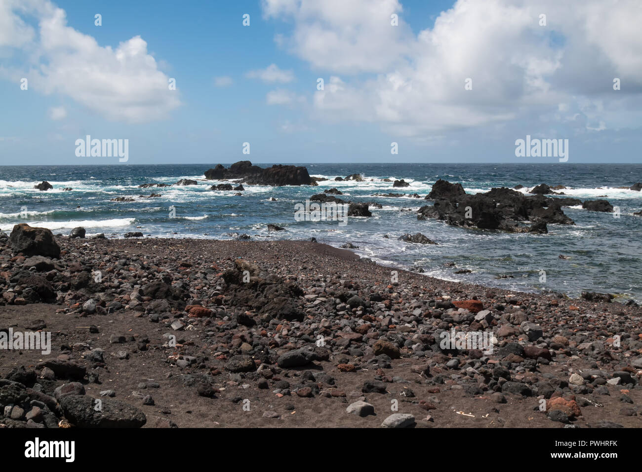 Sharp almost black rocks on the coast of Atlantic ocean. Small waves ...