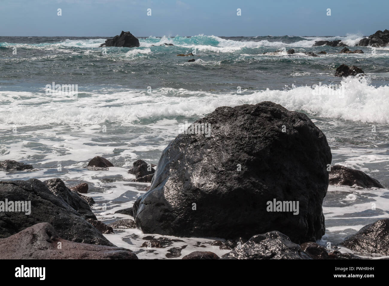 Sharp almost black rocks on the coast of Atlantic ocean. Small waves ...