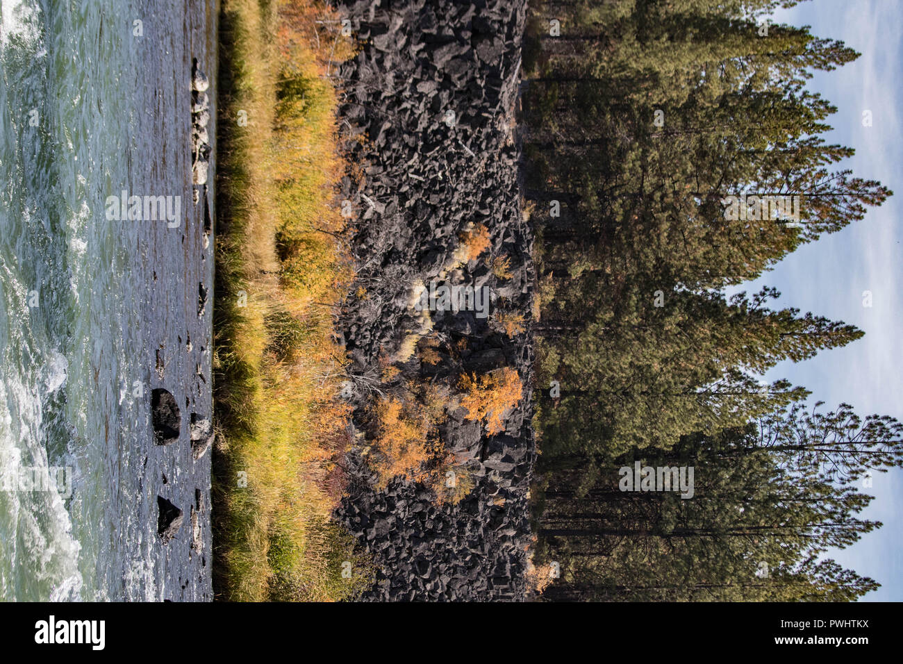 A talus slope gives way to bright fall foliage on the bank of the Deschutes River in Oregon. Stock Photo