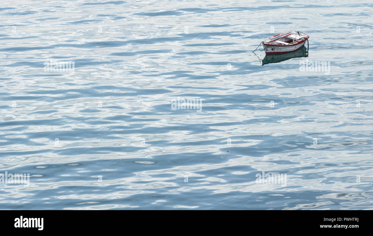Small rowing boat on calm water in northern Spain, framed in the top right corner. Stock Photo