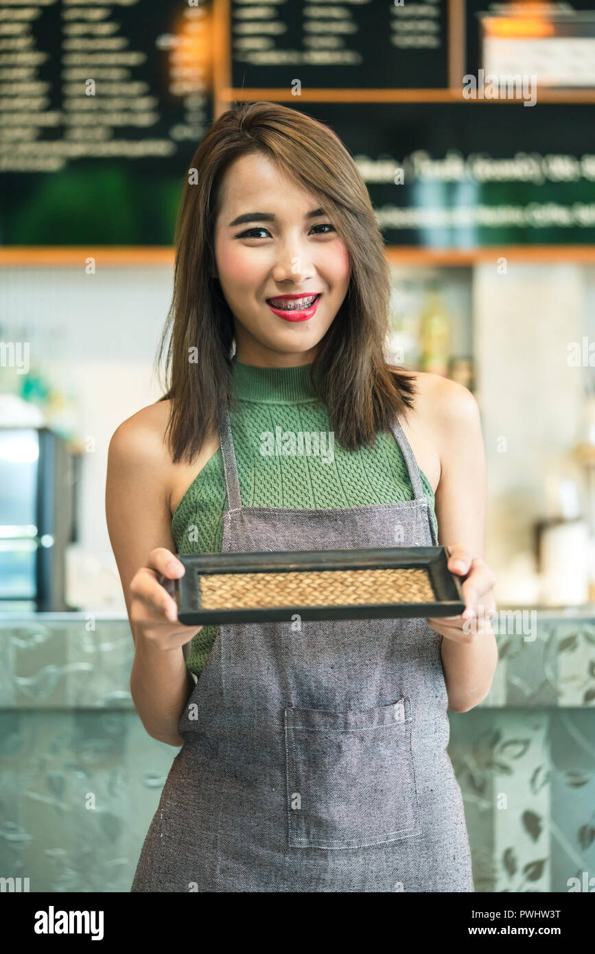 Young woman bartender holding empty tray in coffee shop Stock Photo
