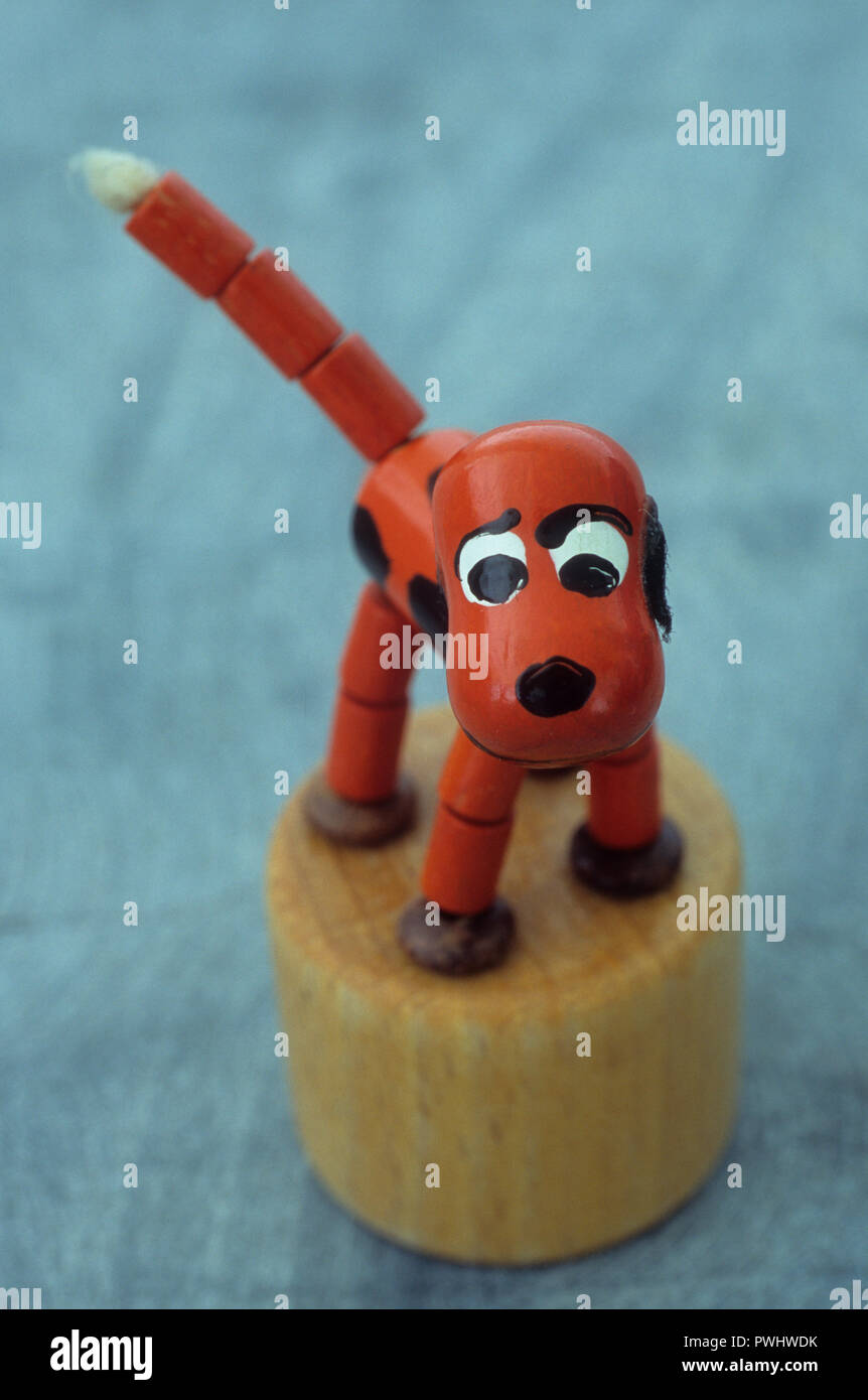Wooden orange dog model with cheeky expression standing on wood base squeezable to make it move Stock Photo