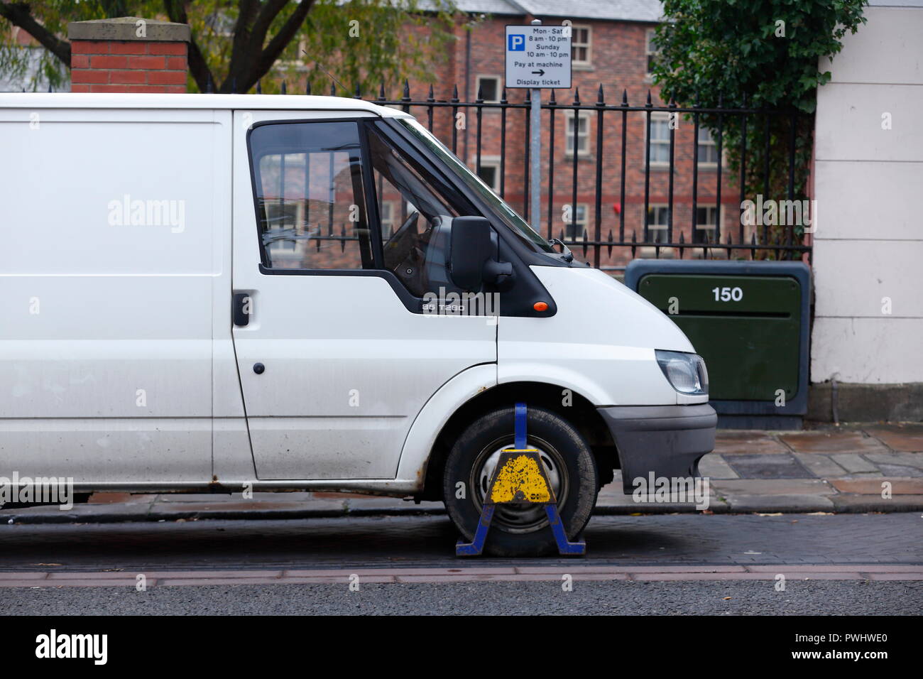 A vehicle with a wheel clamp attached due to a parking offence Stock Photo