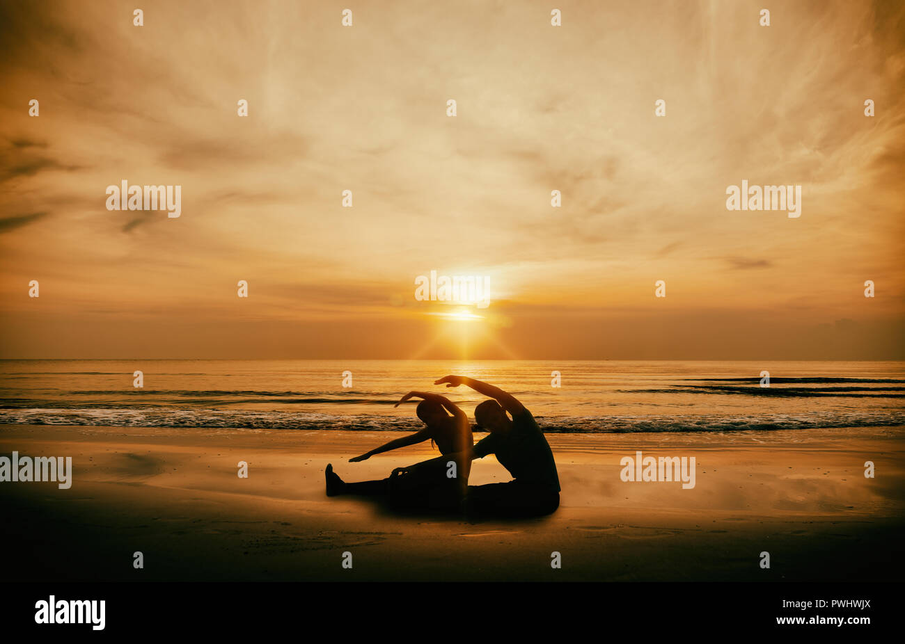 Silhouette Asia woman and man yoga on the beach at sunrise. Stock Photo