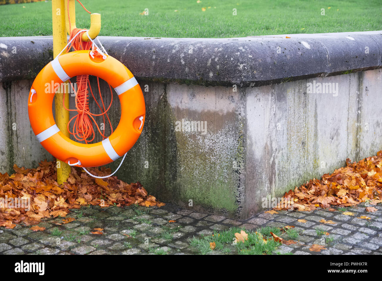 Orange buoy ring hanging at sea coast for water safety Stock Photo