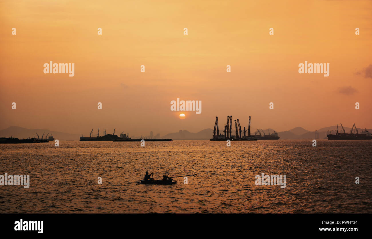 Landscape view of Industrial ship at sunset with fishing boat Stock Photo