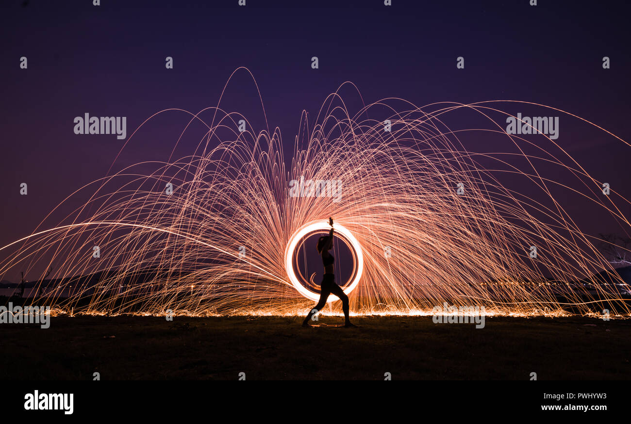 Silhouette Asia woman yoga on the beach at sunset with Steel wool spinning background Stock Photo