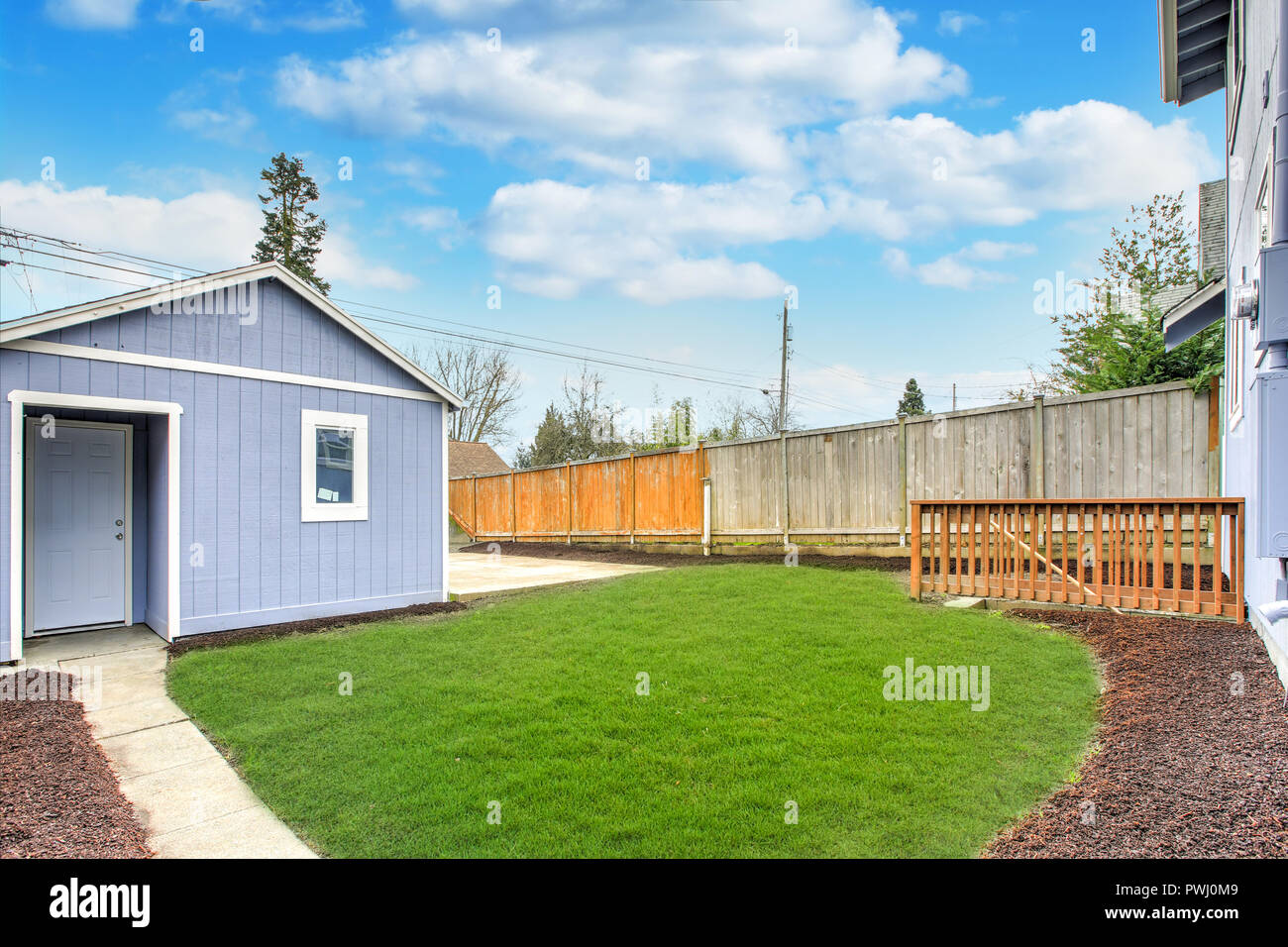 Large fully fenced back yard with green grass and one car detached garage. Stock Photo