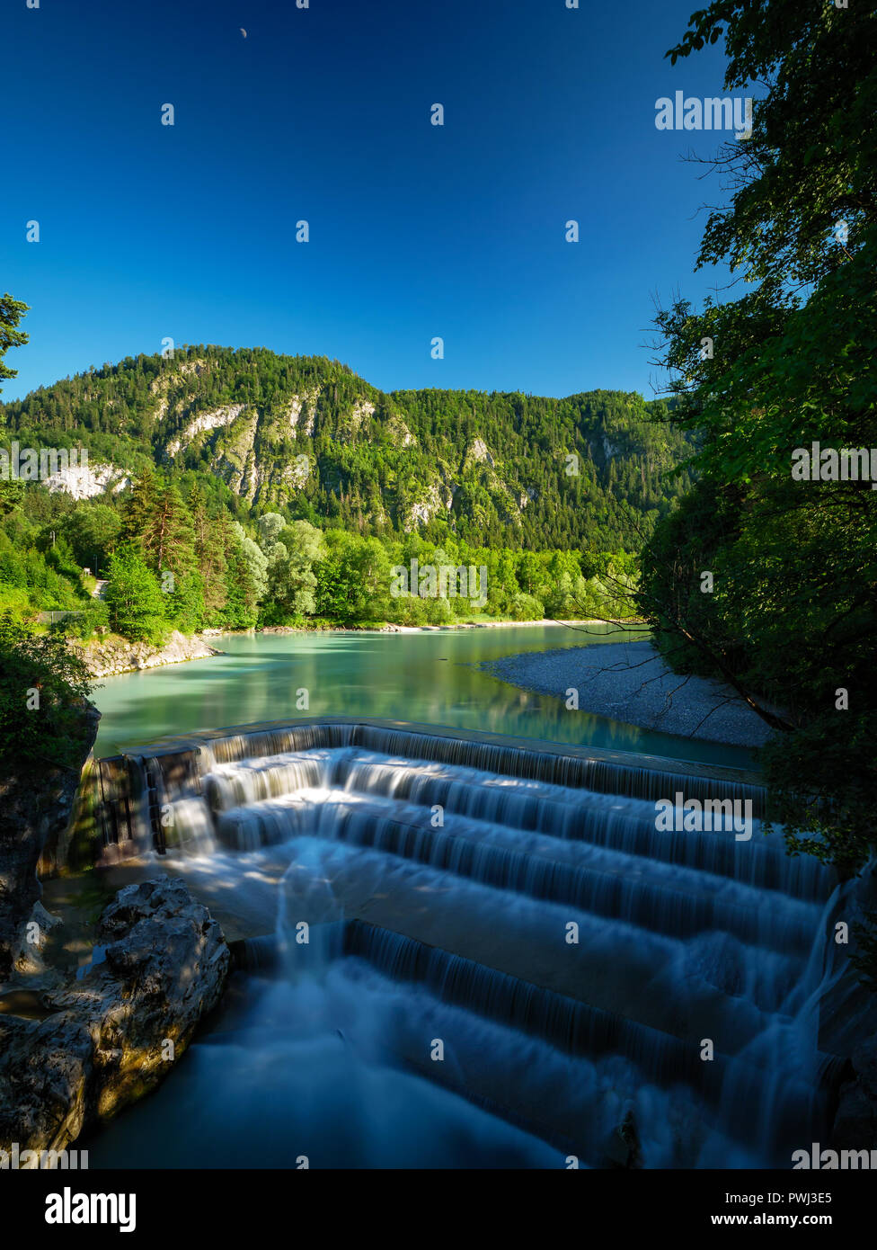 Lechfall in Germany Pfronten Füssen. Waterfall with steps and a blue sky with the moon in the Background. Also some green trees you can see. Stock Photo
