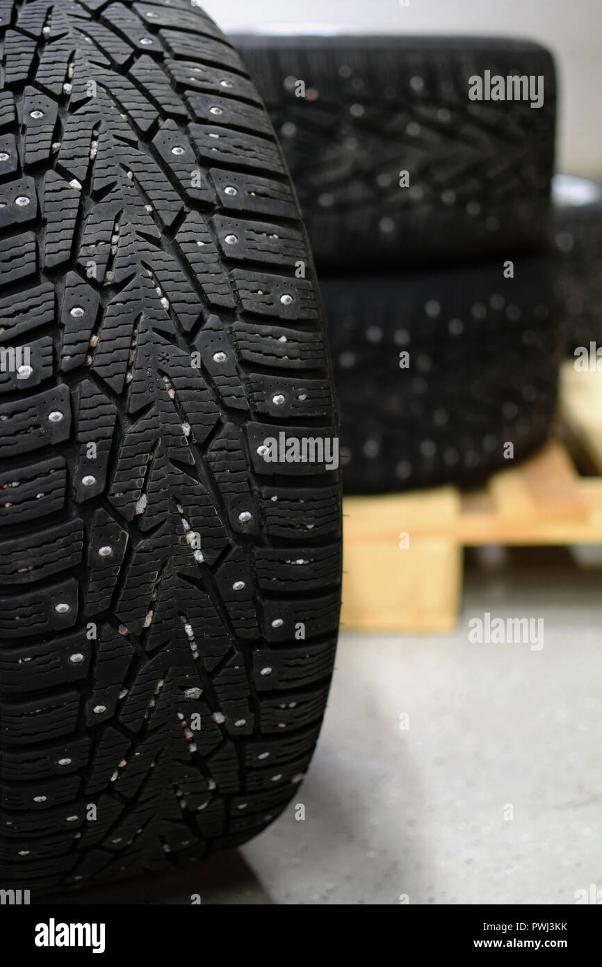 Snow tire with metal studs in garage. More tires on background. Vertical image. Stock Photo