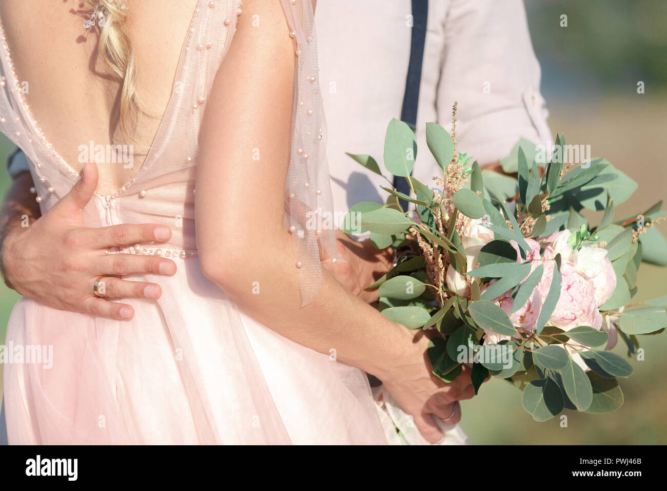Hands of the bride and groom with wedding bouquet Stock Photo - Alamy
