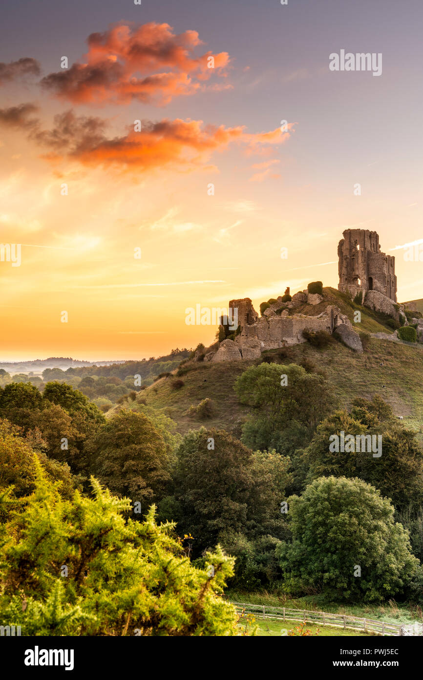 After another cold night, a colourful sunrise over the historic ruins of Corfe Castle heralds the start to rising temperatures in the county of Dorset Stock Photo