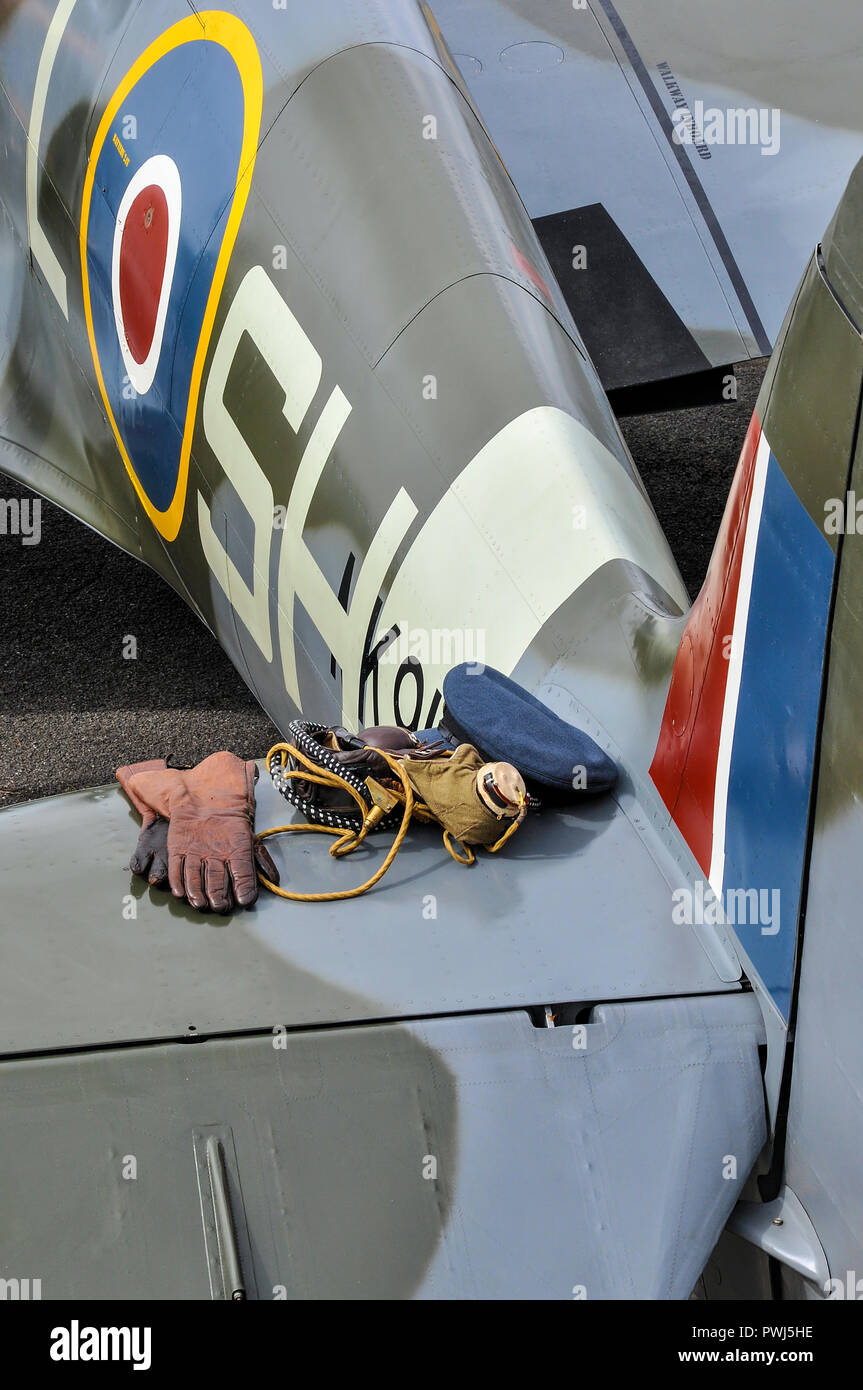 Second World War pilot's equipment ready for flight on the tail plane of a RAF Supermarine Spitfire fighter. Prepared to go. Gloves, cloth helmet, cap Stock Photo