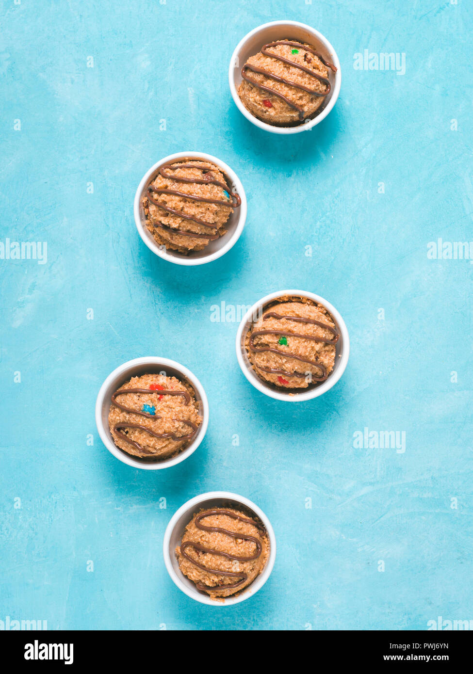 Safe-to-eat raw monster cookie dough in small portion bowl on blue background. Ideas and recipes for kids and toddlers meal. Top view or flat-lay. Cop Stock Photo