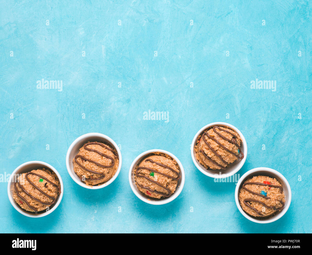 Safe-to-eat raw monster cookie dough in small portion bowl on blue background. Ideas and recipes for kids and toddlers meal. Top view or flat-lay. Cop Stock Photo