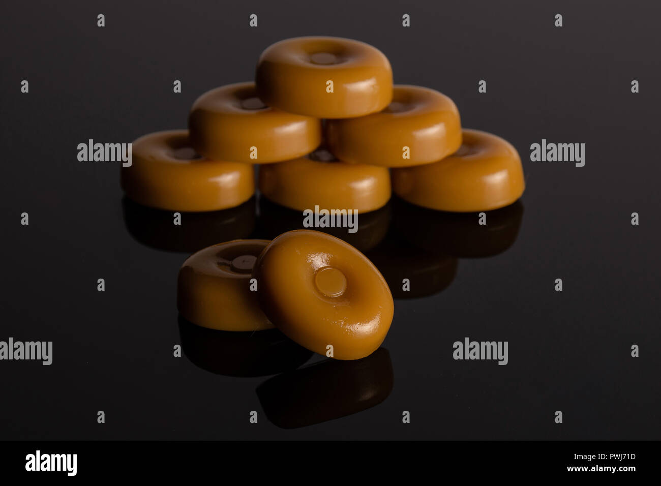 Group of eight whole caramel cream candy butterscotch variety on black