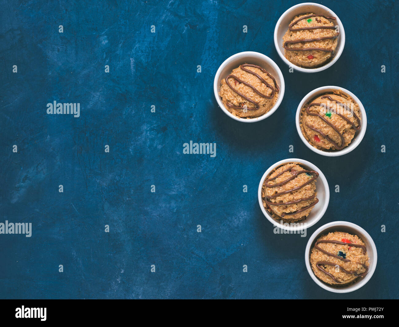 Safe-to-eat raw monster cookie dough in small portion bowl on blue background. Ideas and recipes for kids and toddlers meal. Top view or flat-lay. Cop Stock Photo