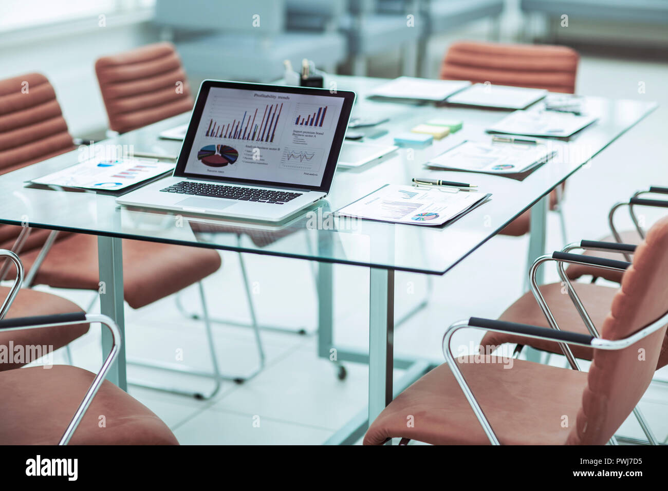 open laptop computer with financial charts and papers spread out on the ...