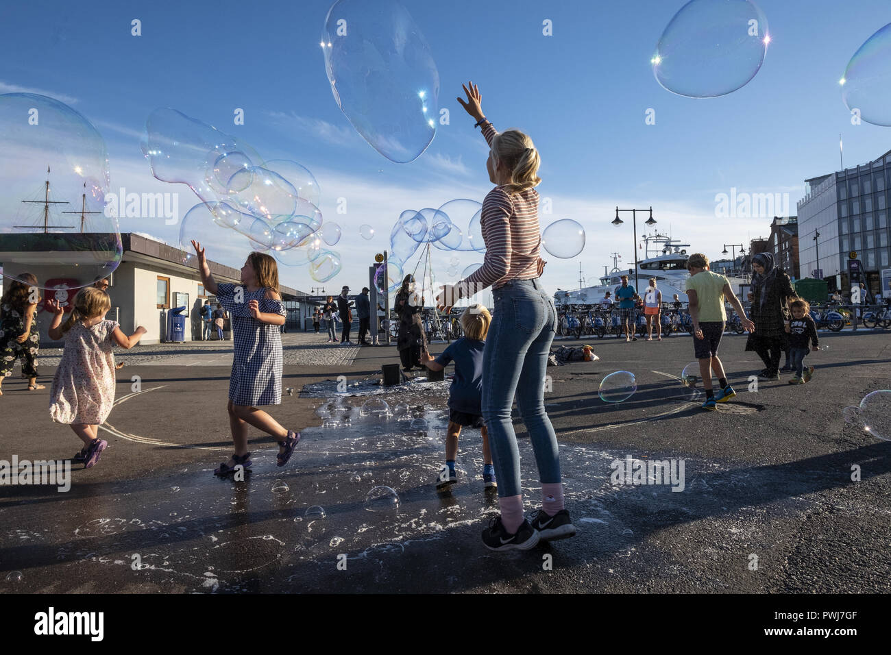 Children are playing with soap bubbles at Aker brygge in Oslo, Norway Stock Photo