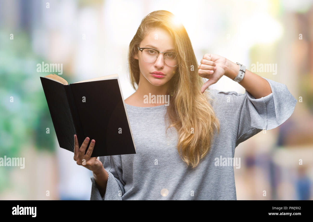 Young beautiful blonde woman reading a book over isolated background ...