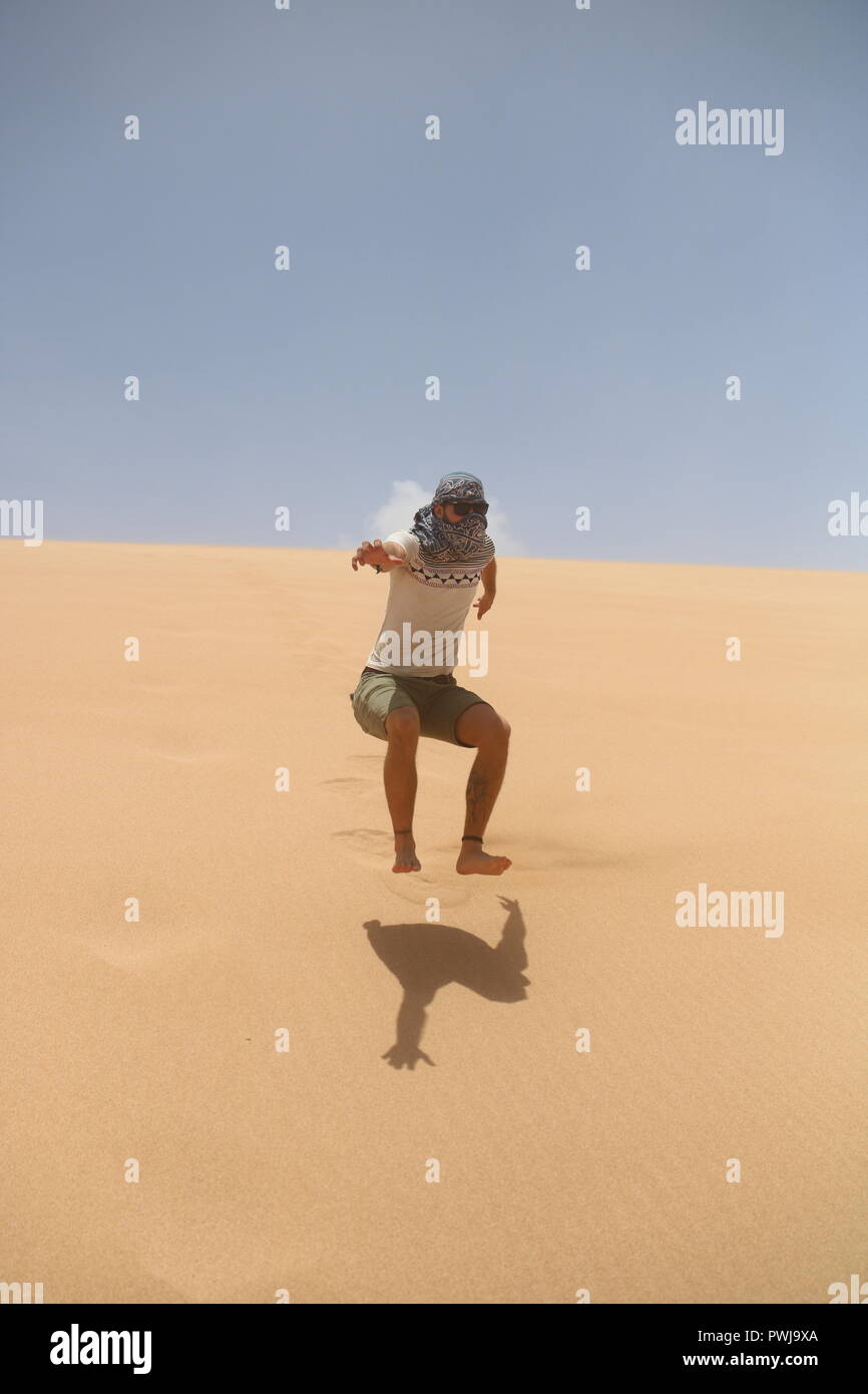 Man jumping of a dune in the desert Stock Photo