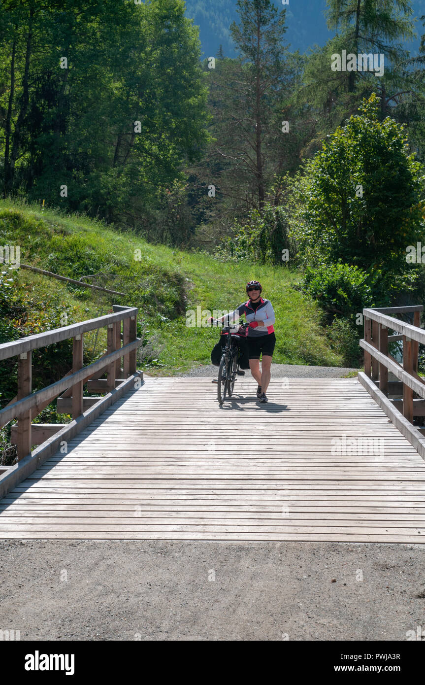 Cyclist crosses a wooden bridge over the Inn river at Scuol in the Swiss canton of Grisons Stock Photo
