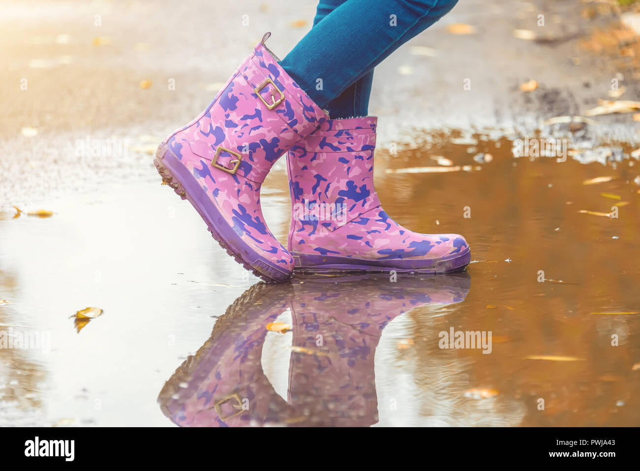 children's feet in rubber boots stand in a puddle in the autumn Stock ...