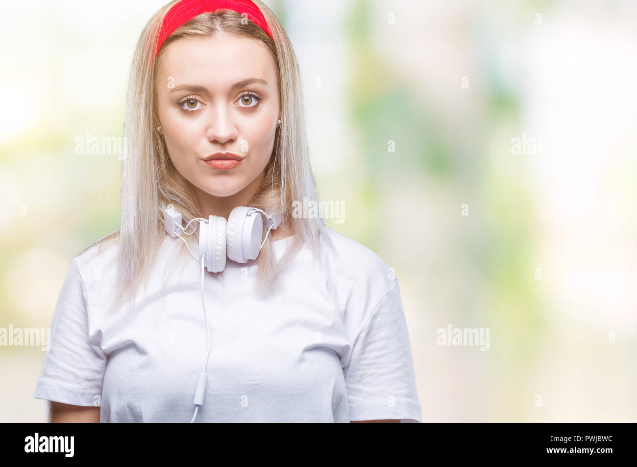 Young blonde woman wearing headphones listening to music over isolated ...