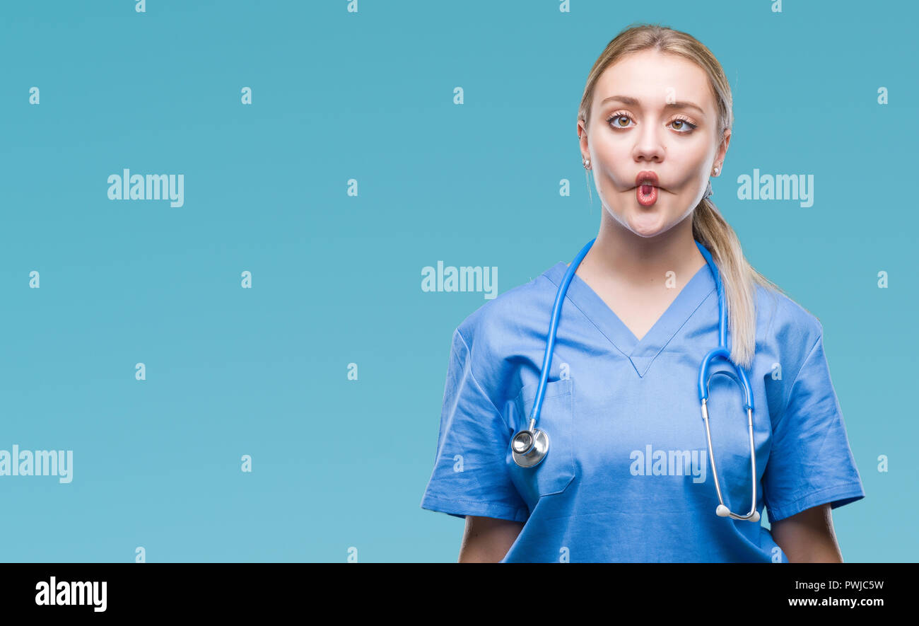 Young blonde surgeon doctor woman over isolated background making fish ...