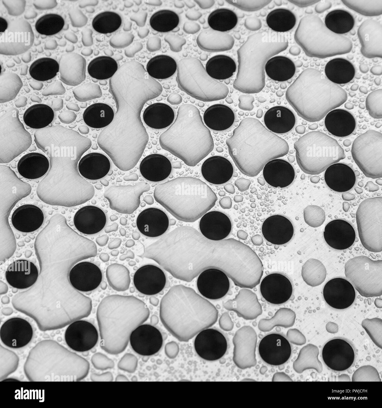 Post-rainstorm water drops on perforated stainless steel sheet. Metaphor for trypophobia. Metal with water drops on it. Water as commodity. Stock Photo