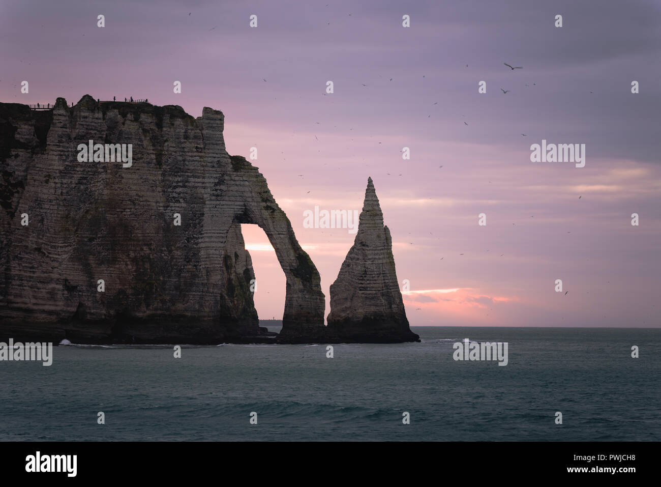 One windy and cold purple evening in Etretat, Normandy, France, famous rocks and cliffs at sunset Stock Photo