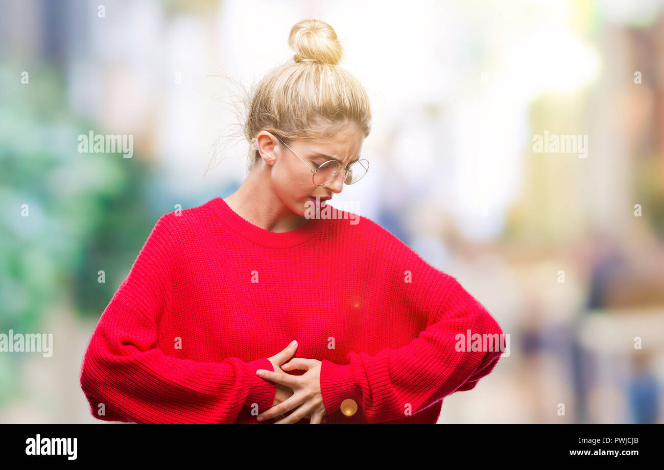 Young beautiful blonde woman wearing red sweater and glasses over isolated background with hand on stomach because indigestion, painful illness feelin Stock Photo
