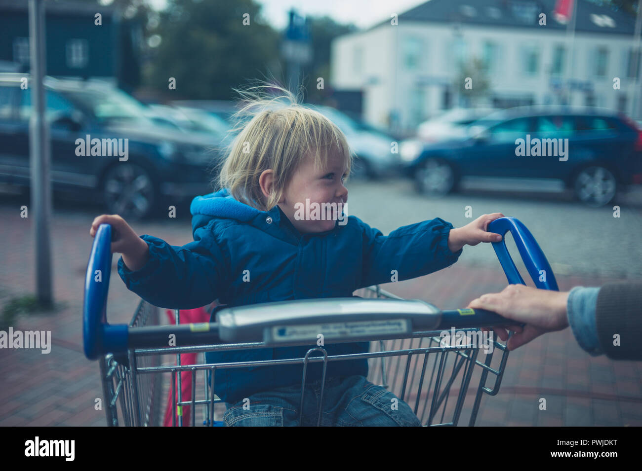 A little toddler is having fun riding in a shopping cart Stock Photo ...